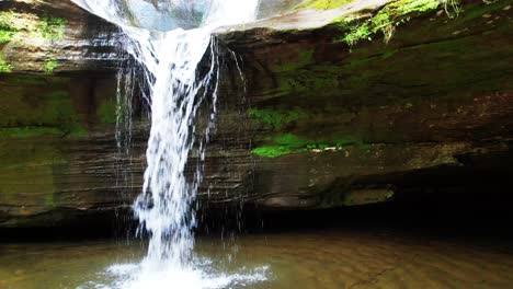 Ein-Drohnenschuss-Verfolgt-Einen-Wasserfall,-Der-In-Einen-Teich-Mündet