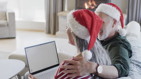 middle aged caucasian couple with laptop with blank screen at christmas at home, slow motion