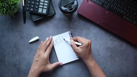person writing notes on a notepad with other office supplies