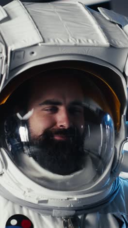 vertical video portrait of happy astronaut holding helmet in orbital station