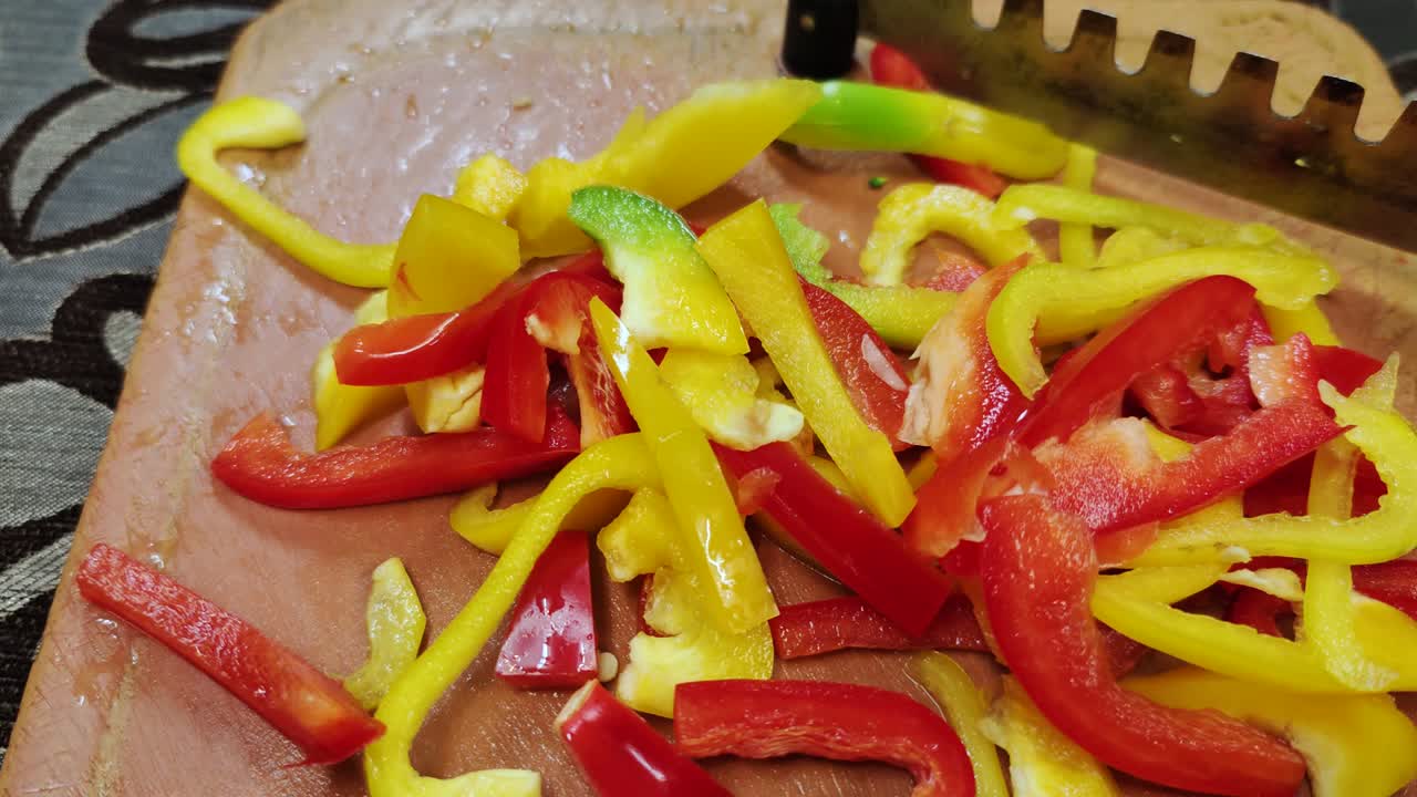 pimienta roja y amarilla fresca picada en un cortador de verduras marrón con una hoja de acero inoxidable