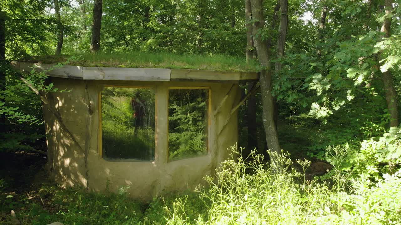 toma panorámica de una pequeña casa de arcilla con techo de pasto en el bosque, verano, bulgaria