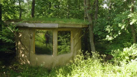 Panning-shot-of-small-clay-house-with-grass-roof-in-forest,-summertime,-Bulgaria