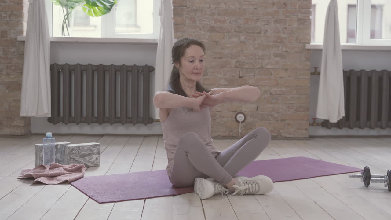 anciana estirándose en una alfombra de yoga en casa