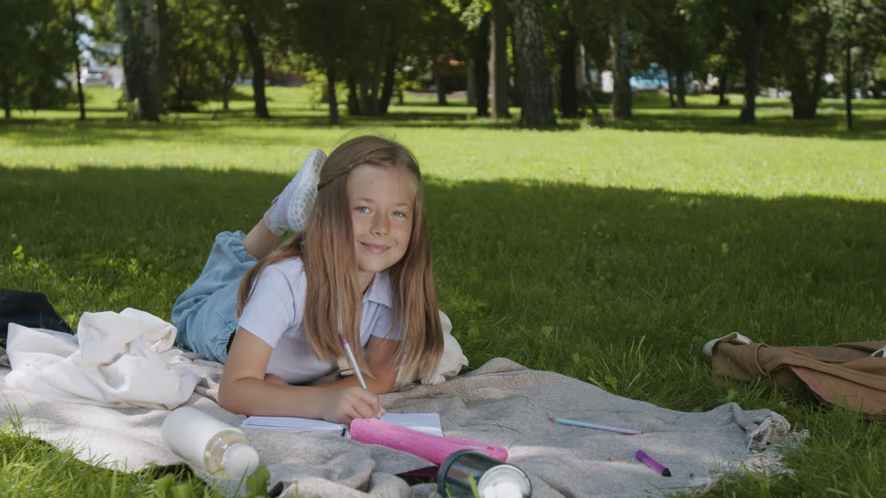 Happy Young Girl Writing and Learning Outdoors in a Park