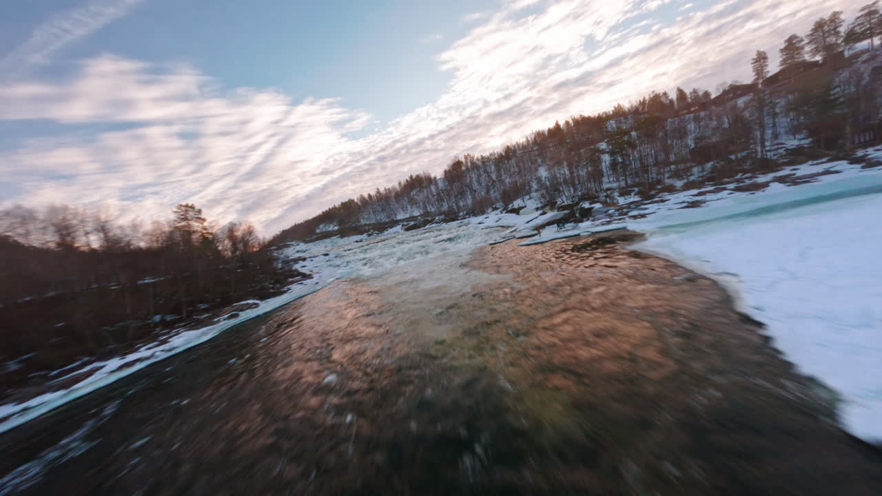 Frozen Målselvfossen river with snow-covered ice and surrounding winter forest