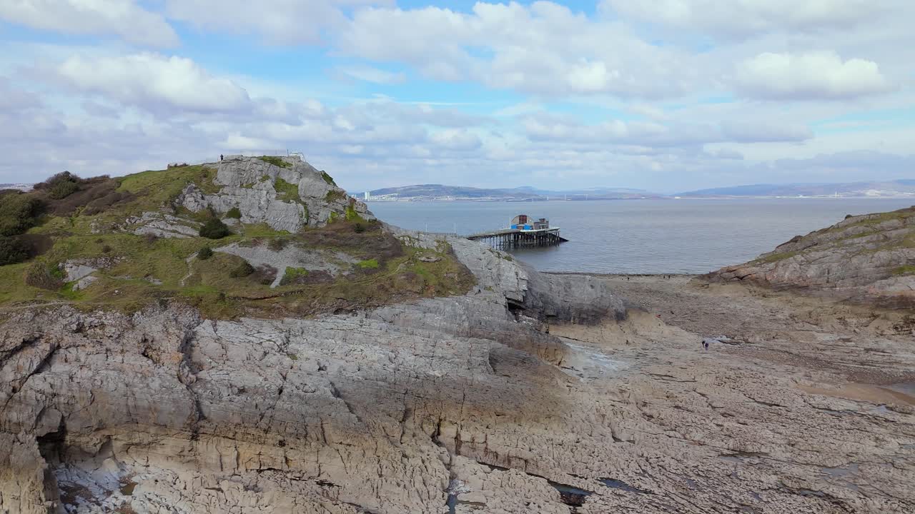 Aerial view of rocky terrains with The Big Wheel at Mumbles Pier Swansea during daytime in United Kingdom.