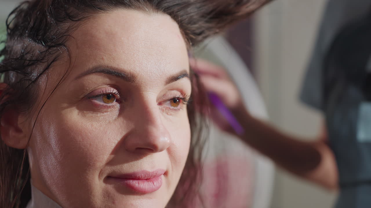 Påføring af hårfarve, en professionel stylist påfører en levende hårfarve, en dygtig kosmetolog farver forsigtigt håret i en salon, en professionel farveekspert påfører omhyggeligt nuancen i en indbydende atmosfære