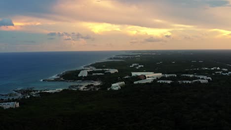 stunning aerial drone shot of a tropical mexican coastline line full of vacation resorts in riviera maya between tulum and cancun during a warm golden yellow summer sunset