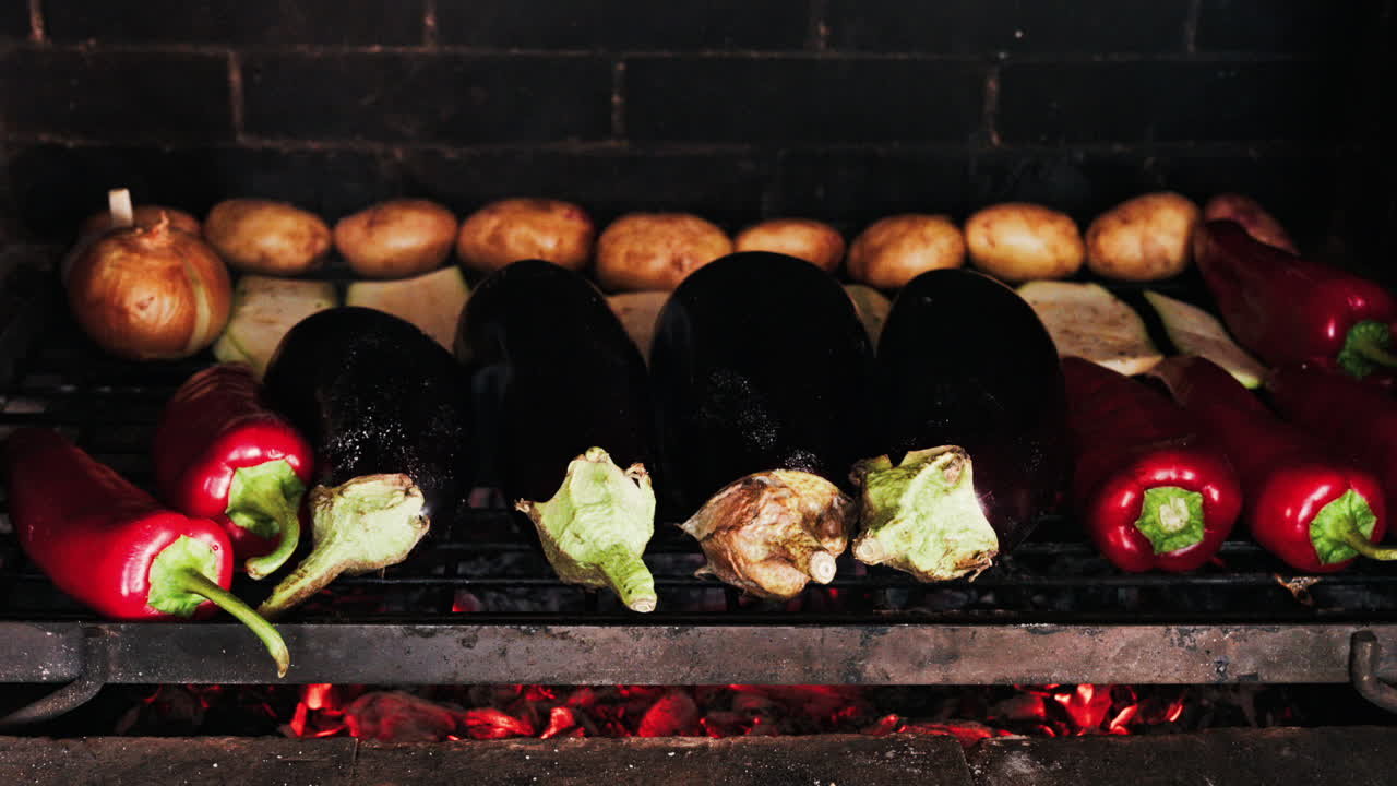 Close up of eggplants, potatoes, onions, peppers and courgettes cooking on a grill