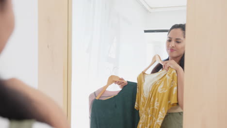 choosing clothes, asian woman holding hangers and deciding outfit in dressing room, at home