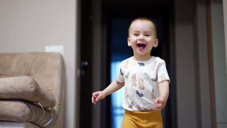 happy caucasian boy runs excitedly about the house. playtime for a toddler at home.