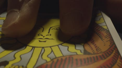 disparo de cerca de una persona que da lectura de cartas del tarot colocando cartas en la mesa con velas y cristales