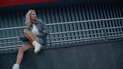 fashionable woman modeling urban background sitting on building.