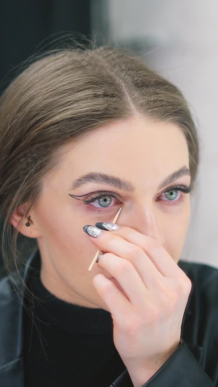 Woman applying or correcting eyeliner