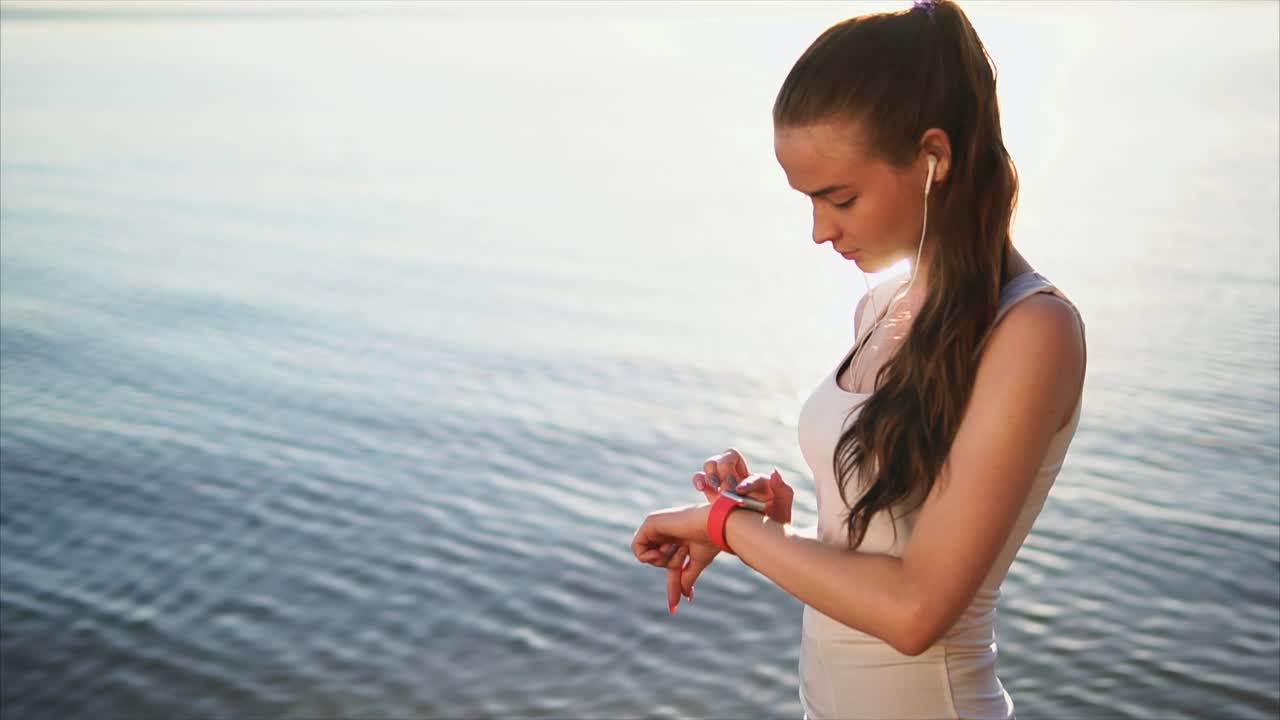 Woman Checking Smartwatch at Sunset Beach
