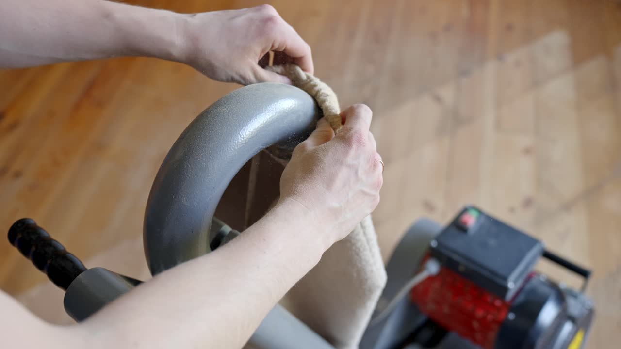 Person attaches dust collection bag to floor sander before beginning restoration work