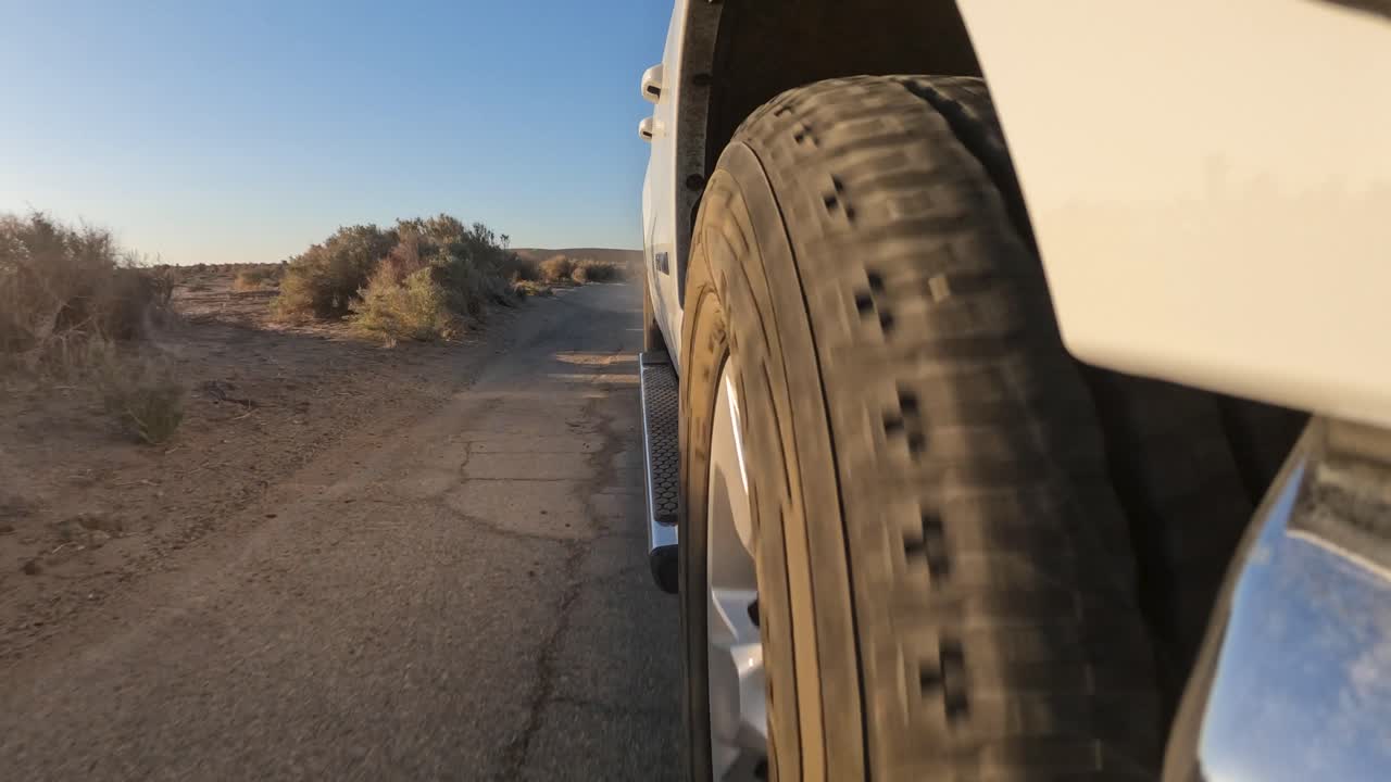 вид под низким углом спереди шины во время движения по ухабистой дороге в пустыне мохаве на закате солнца