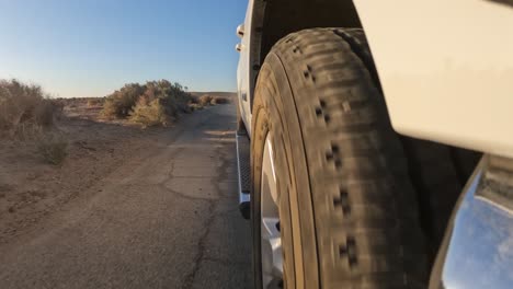 low angle view from in front of the tire while driving down a bumpy road in the mojave desert at sunset