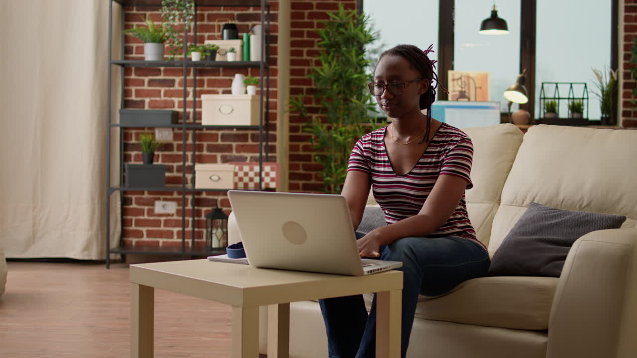 Young African American woman using laptop with headphones in living room