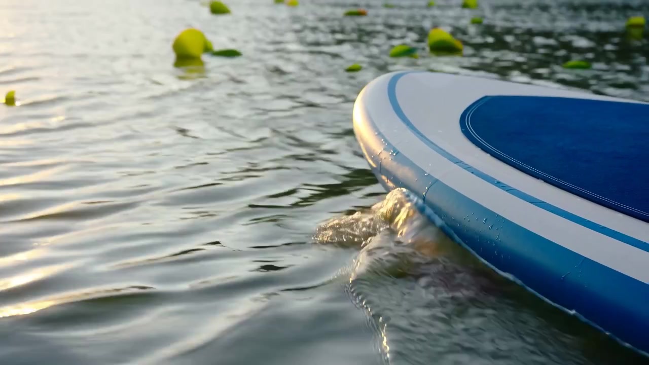 インフレータブルパドルボードの先端が、穏やかな始まりからほぼ終わりまで、浮遊物が点在する穏やかな湖面を横切って着実に進んでいく様子を映したクリップ全体の動きを重視した要約。