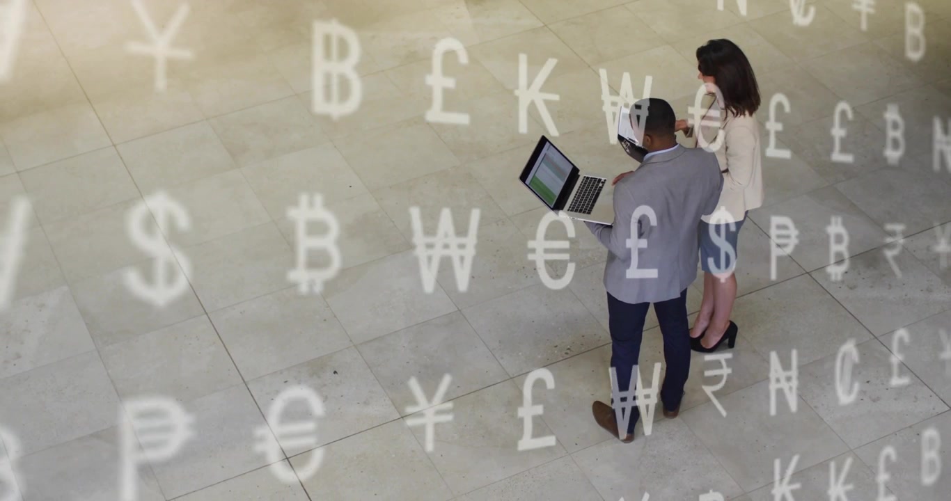 Uomo che inclina il laptop e donna che controlla il tablet nell'atrio, con icone di valuta che indicano dati finanziari