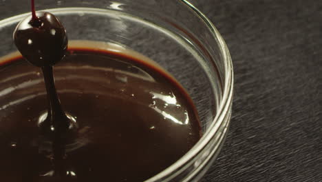 closeup hand immersing cherry in hot chocolate in slow motion