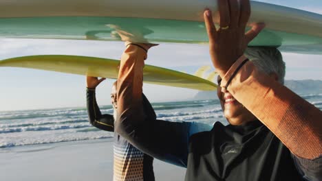 senior african american couple walking with surfboards at the beach