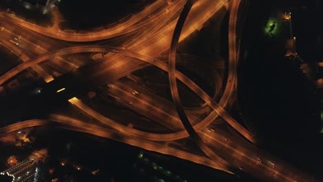 illuminated multi-level road junction and cars traffic at night. drone is spinning around at high altitude. aerial vertical shot.