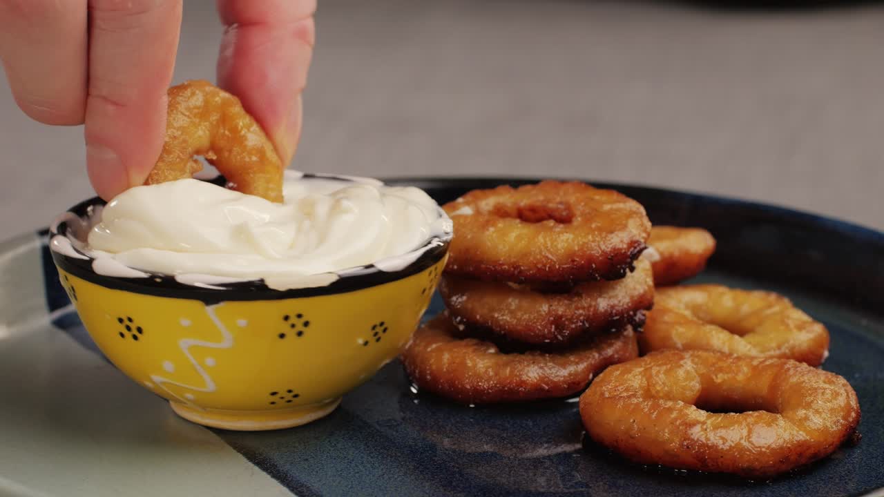 Fried crispy onion rings dipping in white creamy sauce close-up macro. Roasted onion rings for snacks at bar, cafe. Fast food. Delivery. Beer snacks