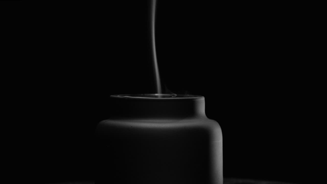 mèche de bougie noire laissant une traînée de fumée après avoir été soufflée, fond noir