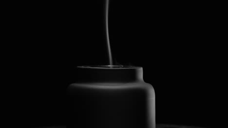 black candle wick leaving a smoke trail after being blown out, black background