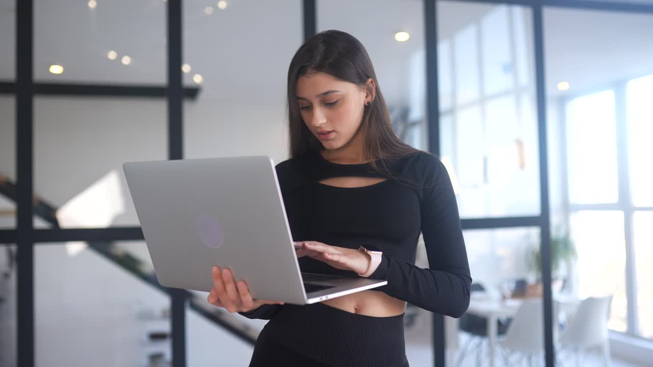 mujer joven trabajando en una computadora portátil en una oficina moderna