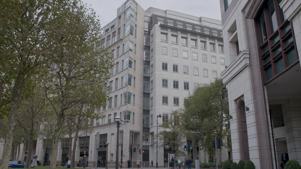 Modern city street with tall buildings, trees, and people walking in the autumn season