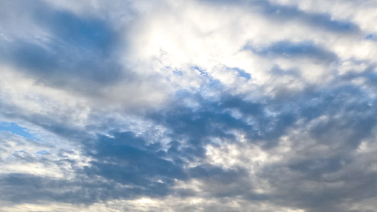 Movement of fluffy clouds along the horizon. Spindrift cloudscape covering the skies and shielding the sun. Timelapse.