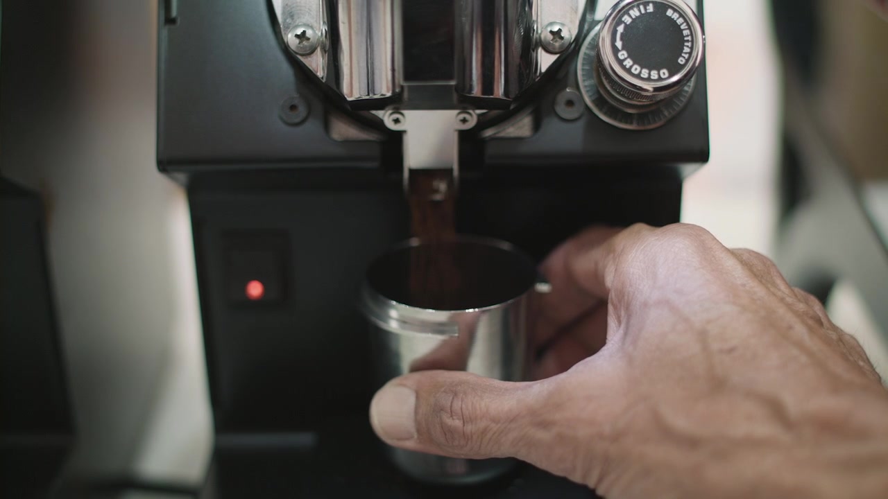 Slow mo close up of coffee grinds coming out of a cafe coffee grinder.