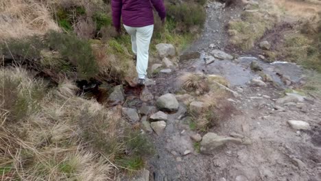 young woman confidently crosses rugged, rocky terrain, showcasing her outdoor skills