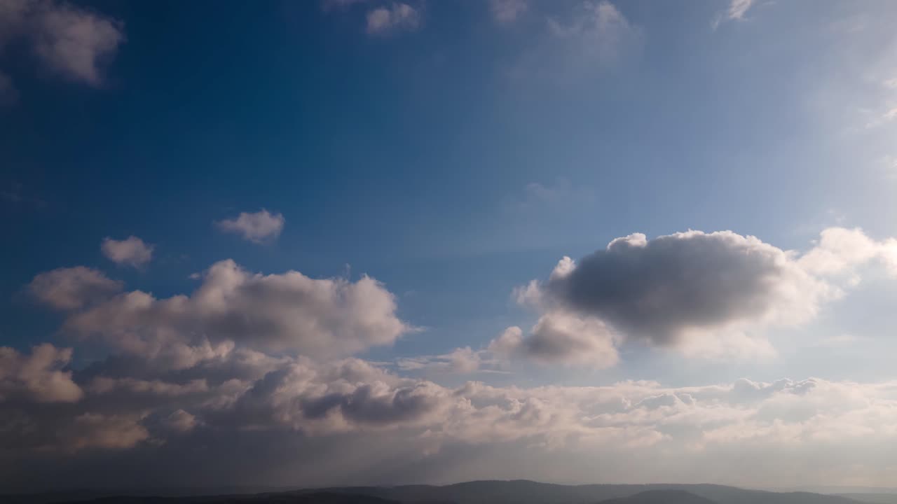Picturesque timelapse of white fluffy clouds moving softly on the clear blue sky.