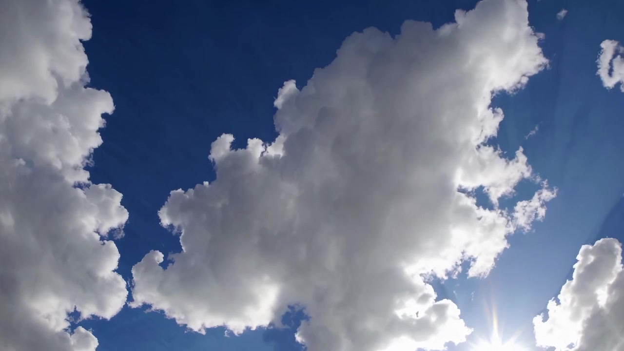 Timelapse de Nuvens Cúmulos Brancas Movendo-se por um Céu Azul com Raios de Sol