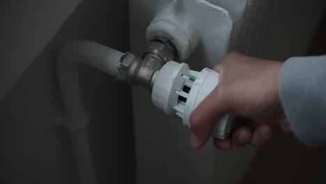 hand turning on thermostatic radiator valve of hot water heating system