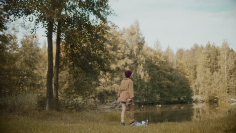 woman walking towards lake in forest