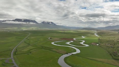 winding river in iceland aerial shot farmlands in countryside cloudy day