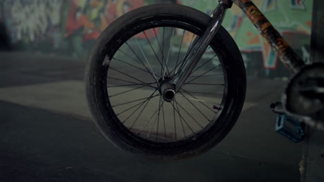 bmx bicycle wheel spinning at skatepark with graffiti wall. bike parking.