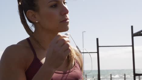 Mujer-Caucásica-Deportiva-Poniéndose-Los-Auriculares-En-Un-Gimnasio-Al-Aire-Libre