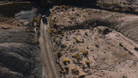 Off-road-vehicle-driving-in-desert-of-Factory-Butte-in-Utah,-USA