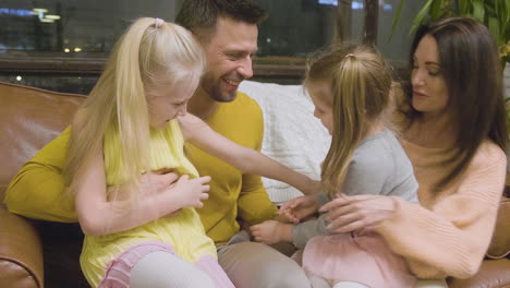 familia feliz haciéndose cosquillas y divirtiéndose mientras se sienta en el sofá en casa 1