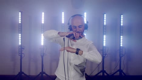 Live-DJ-performance-of-energetic-bald-man-with-headphones,-dancing-on-party-concert-musician-stage