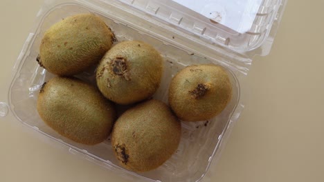 five kiwis in a plastic container