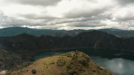 people on mountaintop admiring beautiful crater lake view and volcano scenery in ecuador