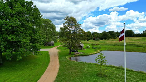 nature retreat, latvia flag waving near lake and wood cabin, recreational ground